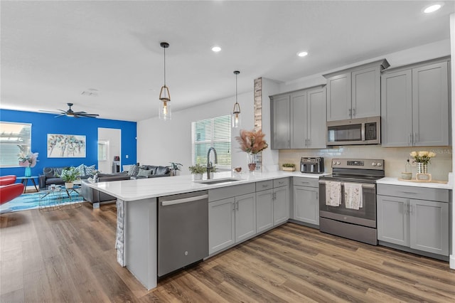 kitchen featuring gray cabinetry, sink, hanging light fixtures, stainless steel appliances, and kitchen peninsula