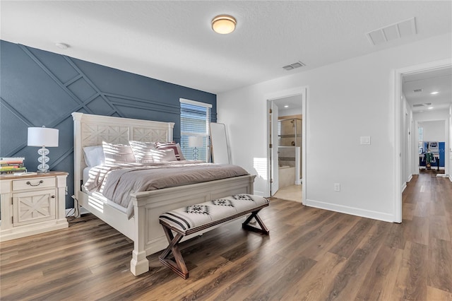 bedroom with ensuite bathroom and dark hardwood / wood-style floors