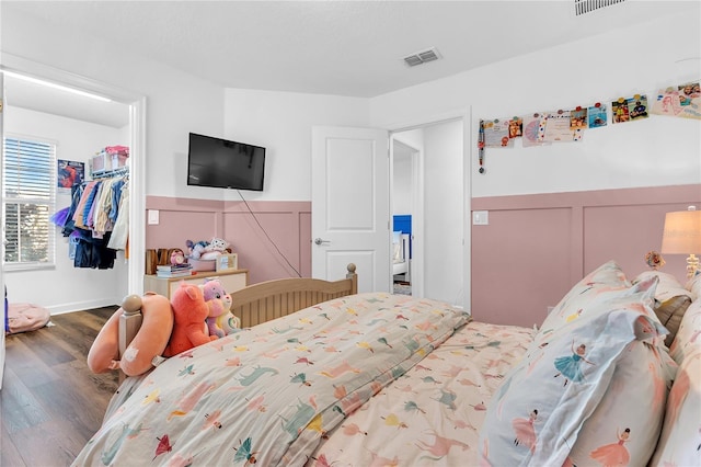 bedroom featuring a spacious closet, wood-type flooring, and a closet