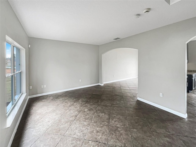 spare room featuring dark tile patterned flooring and a wealth of natural light