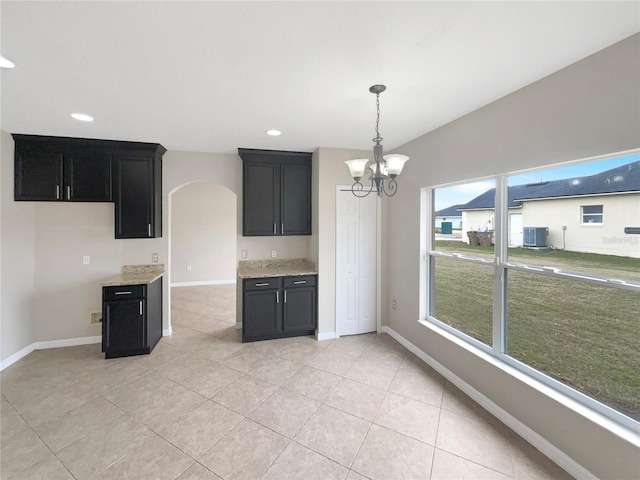 kitchen featuring lofted ceiling, light stone counters, light tile patterned floors, and an inviting chandelier