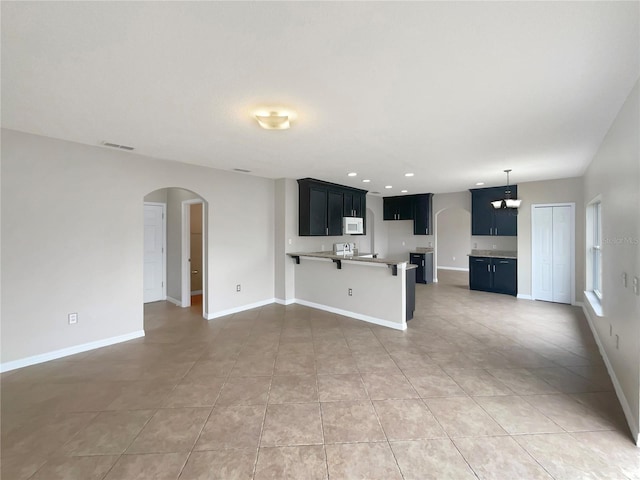 unfurnished living room featuring tile patterned floors and an inviting chandelier