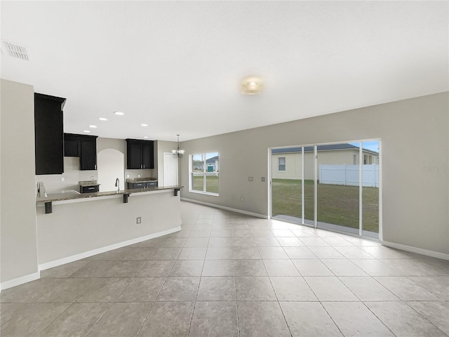 unfurnished living room featuring light tile patterned floors, sink, and a chandelier