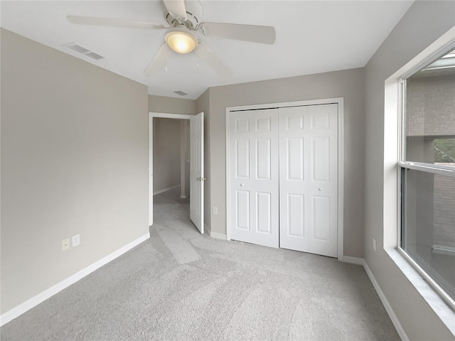 unfurnished bedroom with multiple windows, ceiling fan, a closet, and light colored carpet