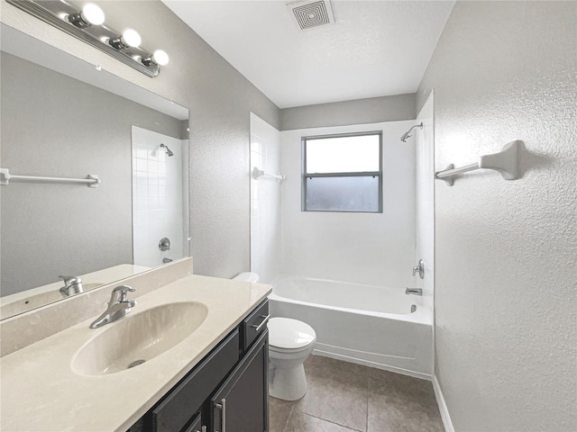 full bathroom featuring vanity, tile patterned floors, tiled shower / bath, toilet, and a textured ceiling