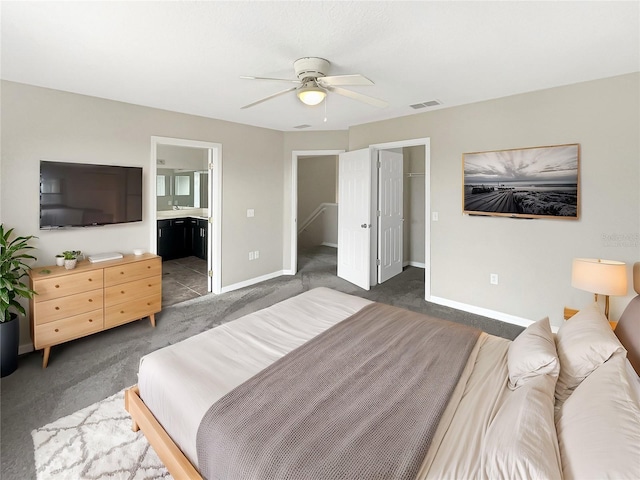 bedroom featuring ensuite bathroom, ceiling fan, and dark colored carpet