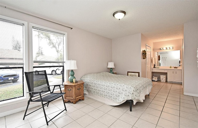 tiled bedroom featuring a textured ceiling and ensuite bathroom