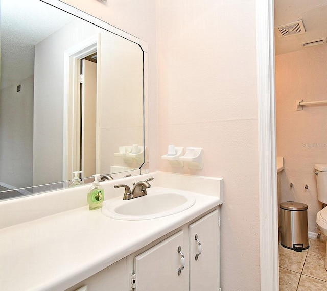 bathroom with tile patterned flooring, a textured ceiling, vanity, and toilet