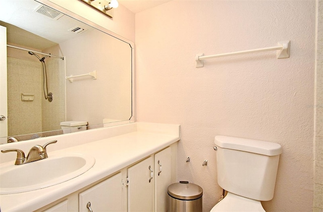 bathroom featuring vanity, toilet, and a tile shower