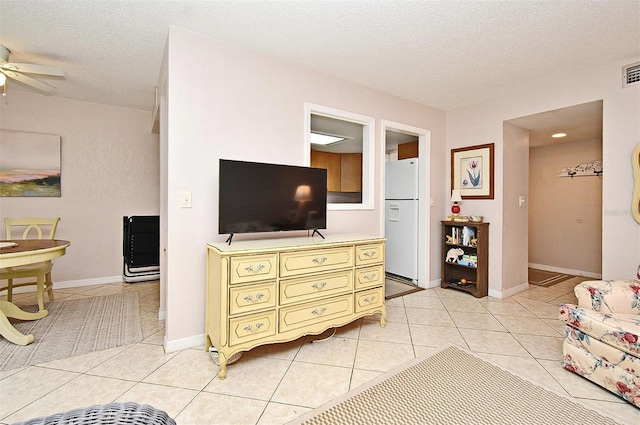 living room featuring light tile patterned floors, a textured ceiling, and ceiling fan