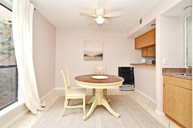 dining space featuring a textured ceiling, ceiling fan, light tile patterned floors, and sink