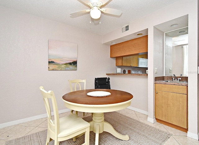 dining area with light tile patterned flooring, ceiling fan, and sink