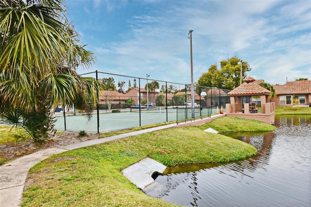 view of tennis court featuring a gazebo and a water view