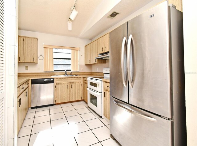 kitchen with light brown cabinets, stainless steel appliances, track lighting, and sink