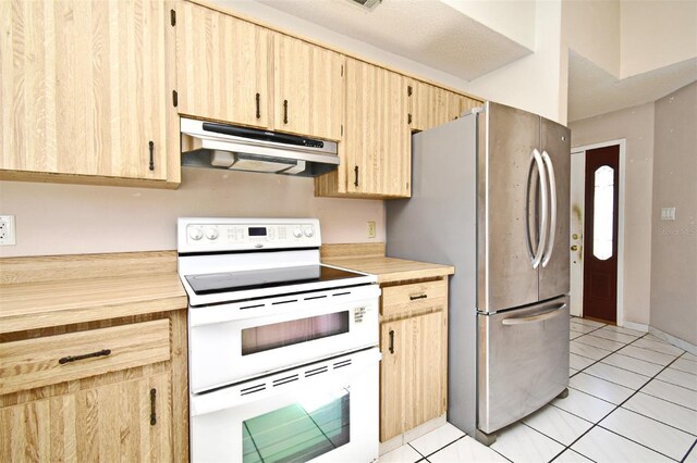 kitchen featuring light tile patterned floors, light brown cabinetry, white electric stove, and stainless steel refrigerator