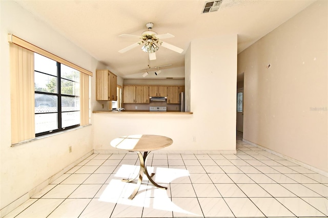 kitchen with light brown cabinets, lofted ceiling, exhaust hood, light tile patterned floors, and kitchen peninsula