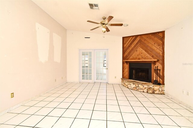 unfurnished living room featuring ceiling fan, light tile patterned flooring, a fireplace, and wooden walls