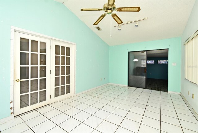 tiled empty room featuring ceiling fan, track lighting, and vaulted ceiling