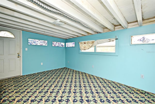 carpeted empty room with beamed ceiling