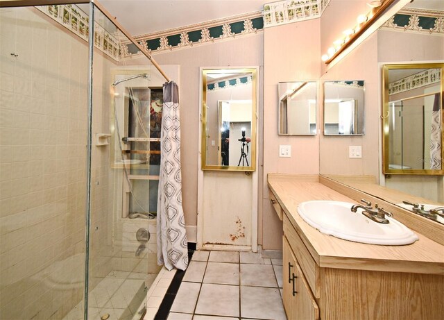 bathroom with tile patterned flooring, a tile shower, and vanity