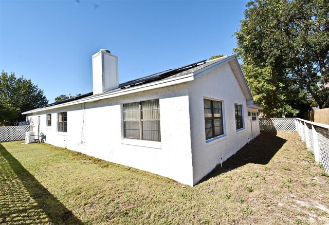 view of property exterior with solar panels and a lawn