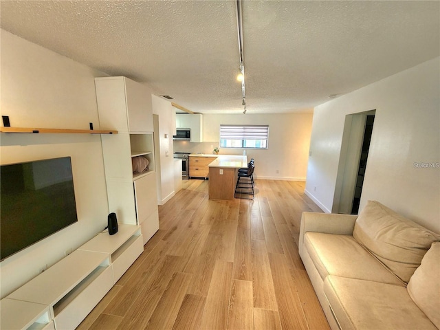 living room with track lighting, a textured ceiling, and light hardwood / wood-style flooring