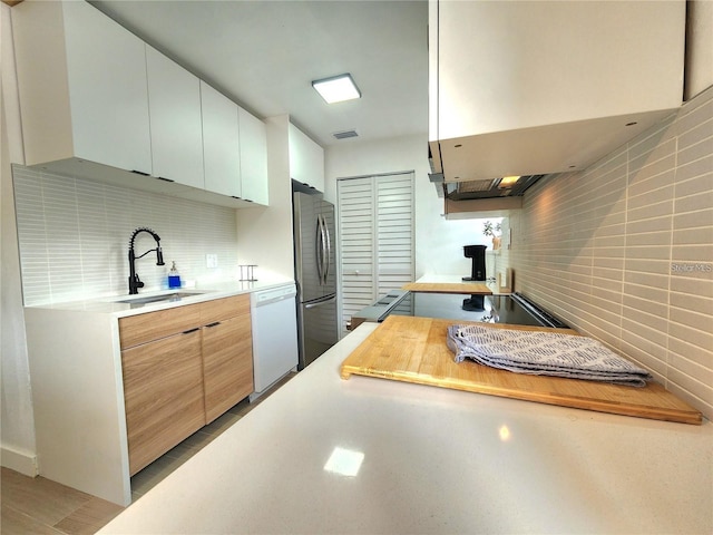 kitchen featuring sink, dishwasher, backsplash, stainless steel fridge, and extractor fan