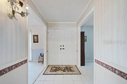 foyer entrance with crown molding and a textured ceiling