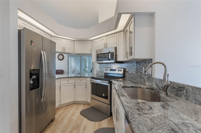 kitchen with stainless steel appliances, sink, stone countertops, light hardwood / wood-style floors, and white cabinetry