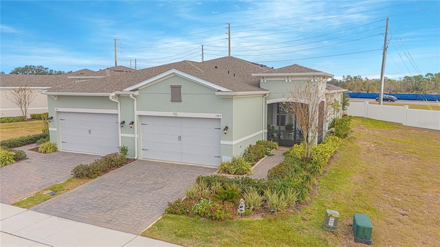 1987 Key Bay Trl, Kissimmee, FL 34747 - view of front of house featuring stucco siding, decorative driveway, a garage, and a shingled roof