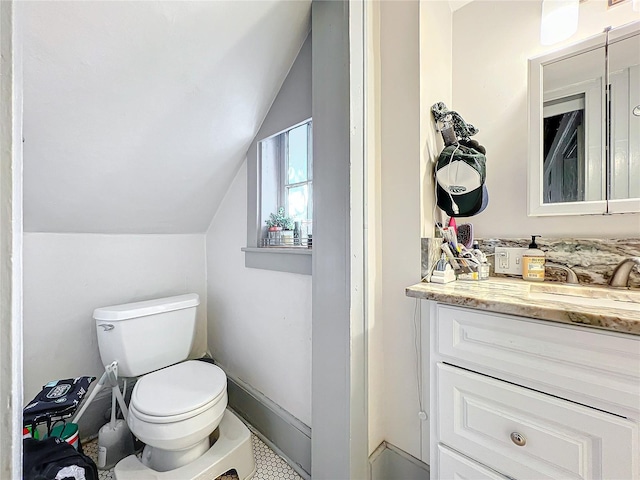 bathroom with toilet, vanity, and vaulted ceiling