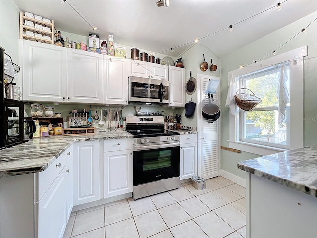 kitchen with light stone countertops, appliances with stainless steel finishes, light tile patterned floors, and white cabinetry