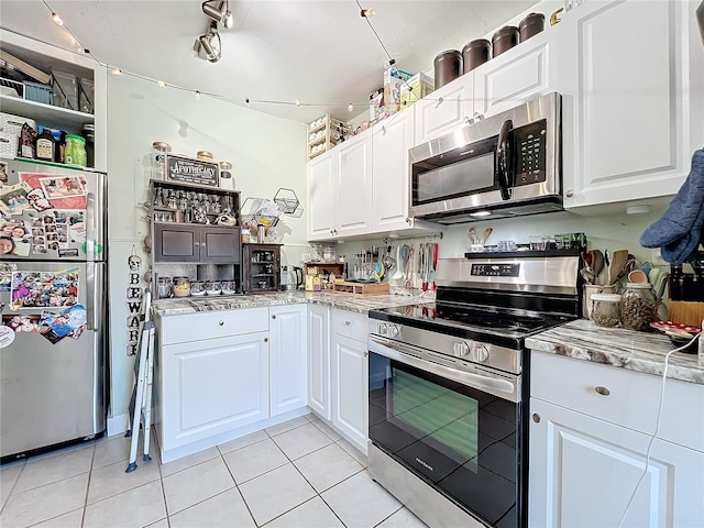 kitchen with light tile patterned floors, white cabinetry, light stone counters, and appliances with stainless steel finishes