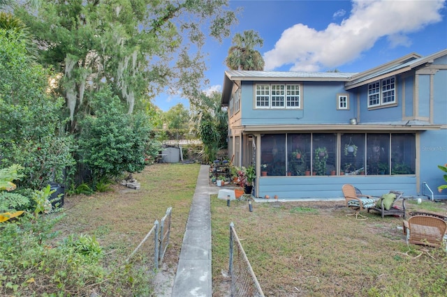 back of property featuring a lawn and a sunroom