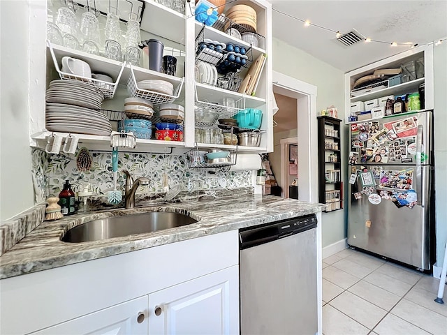 kitchen featuring white cabinetry, sink, stainless steel appliances, light stone counters, and light tile patterned floors