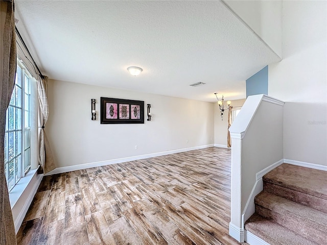 interior space with wood-type flooring, a textured ceiling, and an inviting chandelier