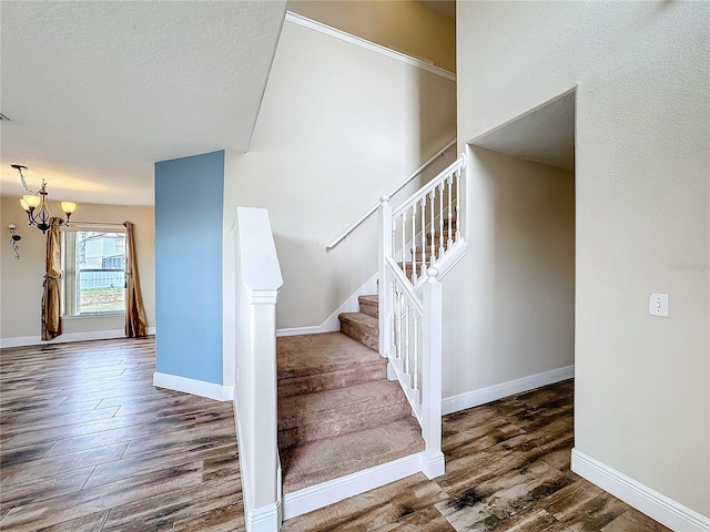 stairway with hardwood / wood-style floors and an inviting chandelier