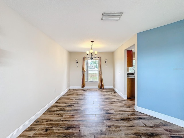 unfurnished dining area with dark hardwood / wood-style floors and an inviting chandelier