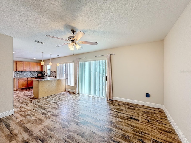 kitchen featuring ceiling fan, tasteful backsplash, hardwood / wood-style floors, pendant lighting, and a kitchen island