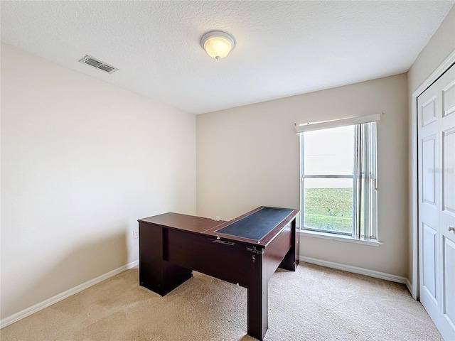 carpeted home office featuring a textured ceiling