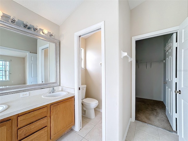 bathroom with tile patterned flooring, vanity, vaulted ceiling, and toilet