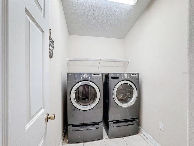 washroom featuring light tile patterned floors, a textured ceiling, and independent washer and dryer