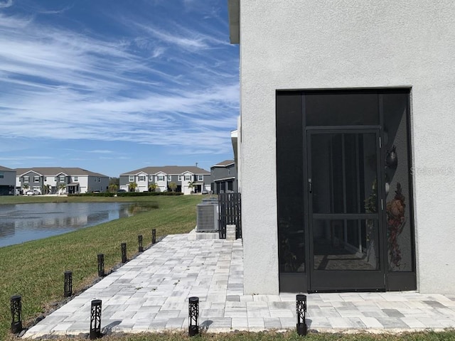 property entrance with a lawn, a water view, and central air condition unit