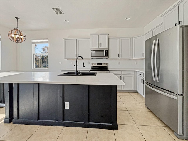 kitchen with a center island with sink, sink, light tile patterned floors, appliances with stainless steel finishes, and white cabinetry