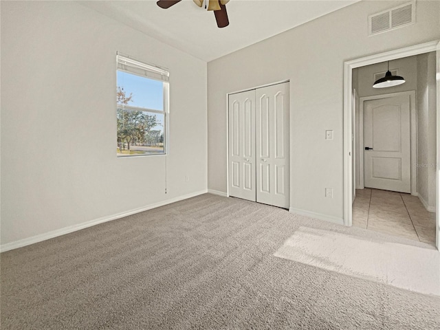 unfurnished bedroom featuring carpet floors, a closet, and ceiling fan