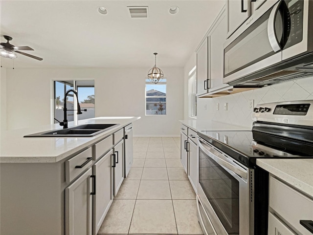 3105 46th St E, Palmetto, FL 34221 - kitchen featuring stainless steel appliances, backsplash, light countertops, hanging light fixtures, and a center island with sink