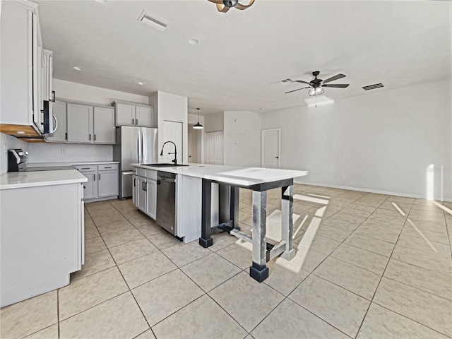 kitchen featuring ceiling fan, pendant lighting, a kitchen island with sink, light tile patterned flooring, and appliances with stainless steel finishes