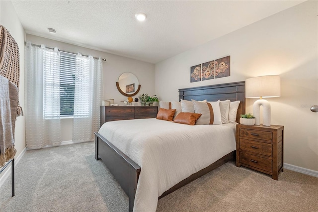 bedroom with light colored carpet and a textured ceiling