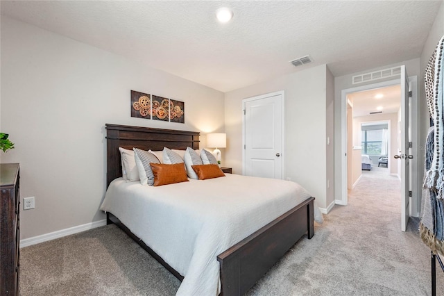 bedroom featuring light colored carpet and a textured ceiling