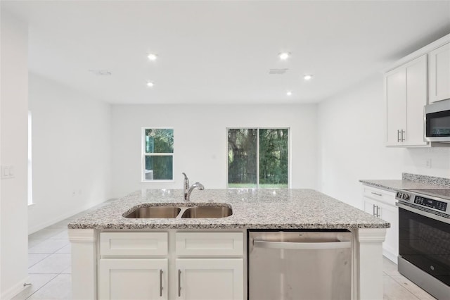 kitchen with sink, light tile patterned floors, a kitchen island with sink, white cabinets, and appliances with stainless steel finishes